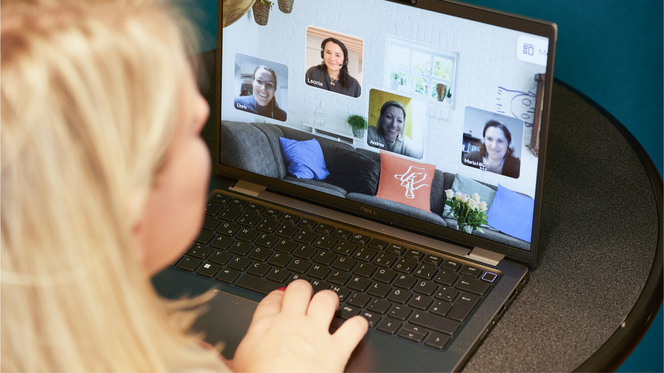 Frau sitzt am Laptop mit geöffnetem Zoom-Fenster und nimmt an einem Treffen im Plauderraum teil.